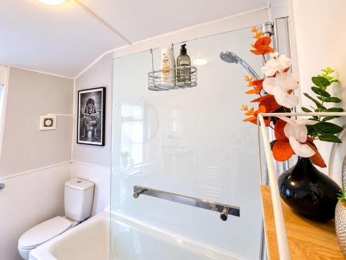 a bathroom with a shower and a toilet and a vase of flowers at Room 2 Shared House 10 min from Center in Liverpool