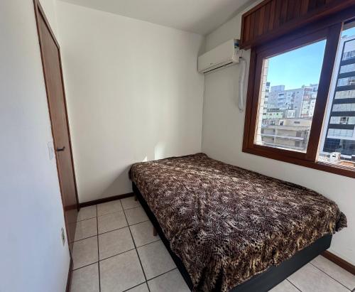 a small room with a bed and a window at Apartamento em Capão da Canoa com Ar-condicionado in Capão da Canoa