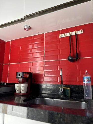 a kitchen with a sink and a red wall at Loft Moderno 3 in Volta Redonda