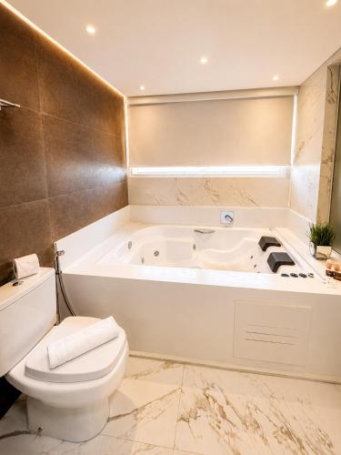a bathroom with a white tub and a toilet at Boulevard Beach Canasvieiras Hotel in Florianópolis