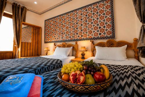 a room with two beds and a bowl of fruit at Yasmin in Bukhara