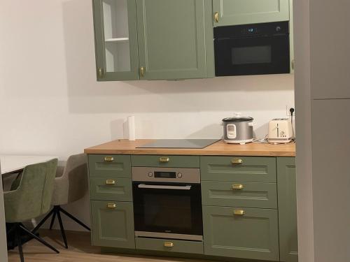 a kitchen with green cabinets and a stove top oven at Edna House in Montigny-lès-Cormeilles