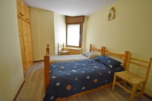 a bedroom with a bed with a blue comforter and a window at MIKI APARTMENT MhD in Madonna di Campiglio