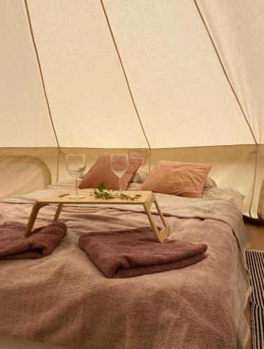 a table on top of a bed with two wine glasses at Mazury Glamping Kruklanki Polana Życzeń in Kruklanki