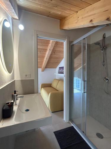 a bathroom with a shower and a sink and a couch at Ecoloft Radici in Poderia
