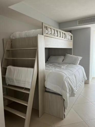 a bedroom with a bunk bed with white sheets and pillows at Bay View Grand Marina with jacuzzi- North Tower in Ixtapa