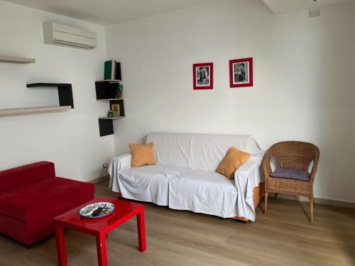 a living room with a white couch and a red table at Genova La casa di Saretta in Marina di Ragusa