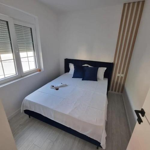 a bedroom with a large white bed with blue pillows at Lux apartmani boka in Tivat