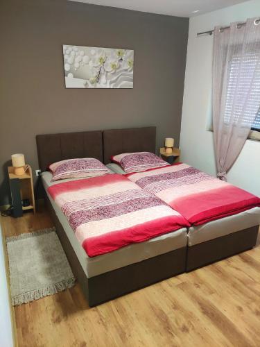 a bedroom with a large bed with red sheets at Apartman LIPA-Lipovac Bajakovo! Parking,Wi-Fi in Lipovac