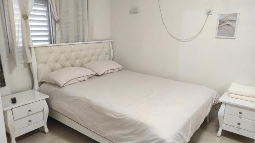 a white bedroom with a bed and a mirror at בית שבט אחים in Hatzor haglilit