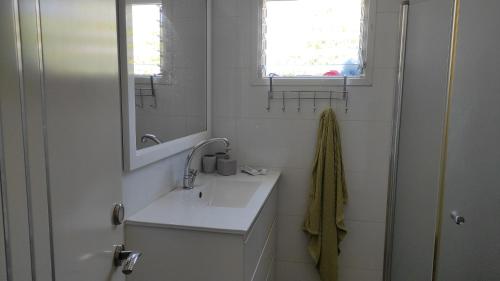 a white bathroom with a sink and a mirror at בית שבט אחים in Hatzor haglilit