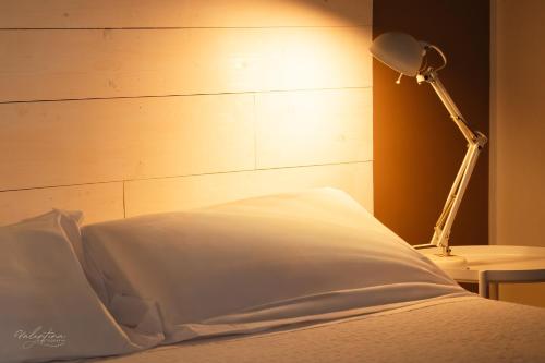 a bed with a white pillow and a lamp at Agriturismo Hornos in Numana