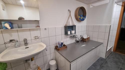 a white bathroom with a sink and a mirror at bed and breakfast Liechti in Wattenwil