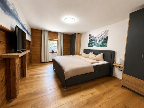 a bedroom with a bed and a flat screen tv at Fritz Alpchalets - Haus Lechtal in Vorderhornbach