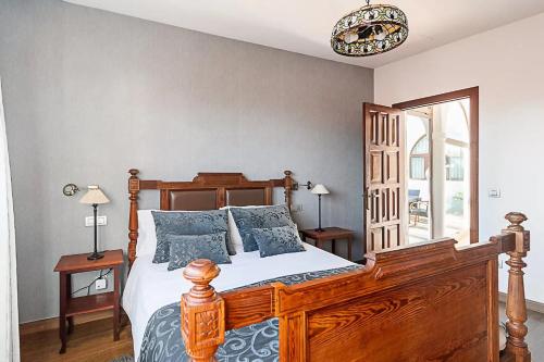 a bedroom with a wooden bed with blue pillows at Casa Huertas del Palmar in Teror