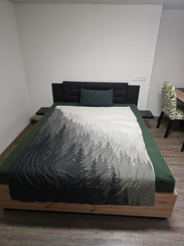 a bed with a bedspread with a painting of trees at Ferienwohnung beim Belchen in Wieden