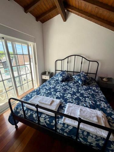 a bedroom with a bed with a blue comforter and a window at Charming Casa Azul - Stay in Historic Chaves in Chaves