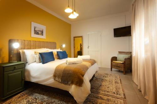 a bedroom with a large bed and a chair at The Old Watchmakers Guest House in Bethulie