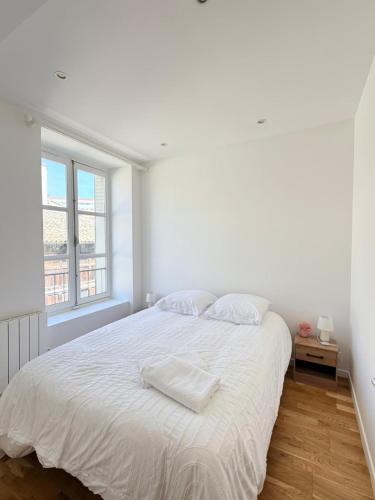 a white bedroom with a large bed and a window at Excellence 2 bedrooms in Saint-Pierre-le-Vieux