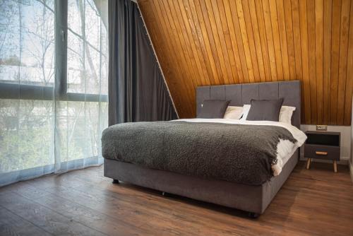 a bedroom with a bed and a large window at AVA Chalet with Jacuzzi in Sinaia