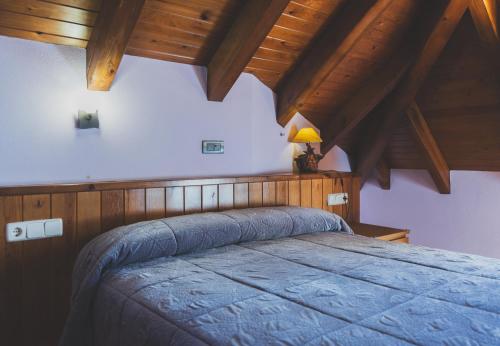 a bedroom with a blue bed with a wooden ceiling at Hotel Rantiner in Taüll