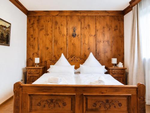 a wooden bed with white sheets and pillows at Kurpark Suite in Bad Rodach