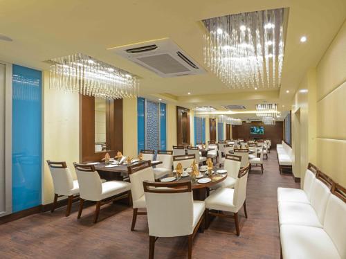 a restaurant with wooden tables and white chairs at Kalinga Hotel in Jodhpur