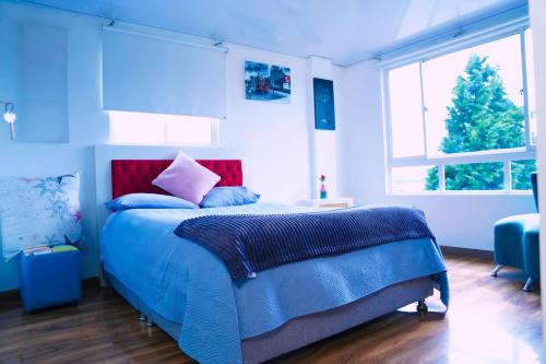 a bedroom with a blue bed with blue sheets and windows at Apartamento THEMIS Tocancipa in Bemposta