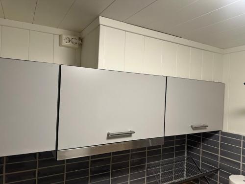 a kitchen with white cabinets and a black tile wall at Fantastic Apartment Tromsø Two in Tromsø