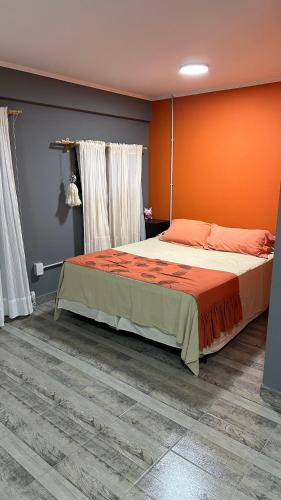a bedroom with a bed with an orange wall at Lo de jota in Ramallo