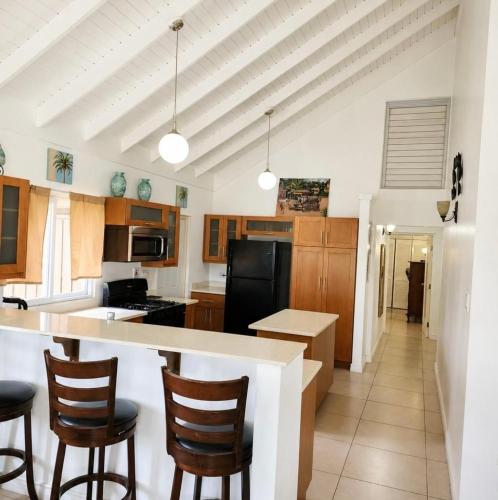 a kitchen with wooden cabinets and a island with bar stools at Willis staycation in Sandy Bay