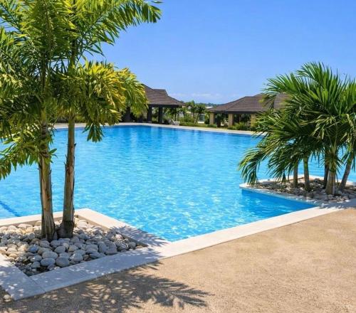 a swimming pool with palm trees in a resort at Willis staycation in Sandy Bay