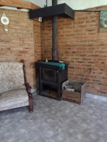 a fireplace in a room with a couch and a chair at Cabaña Paralelo 1 in Viedma