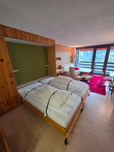 a bedroom with a large bed and a living room at Utoring Acletta B 27 in Disentis