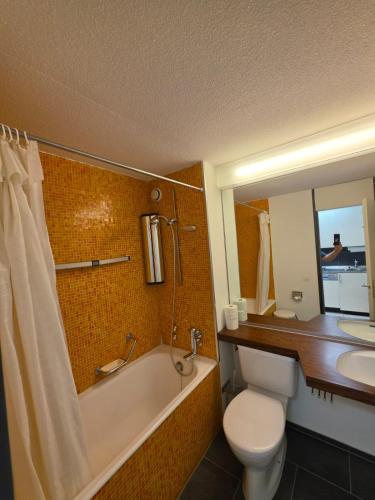 a bathroom with a tub and a toilet and a sink at Utoring Acletta B 27 in Disentis