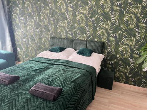 a bedroom with a green bed with two pillows at Picúr és Manó Apartmanjai- Picúr Apartman és Manó Apartman in Baja