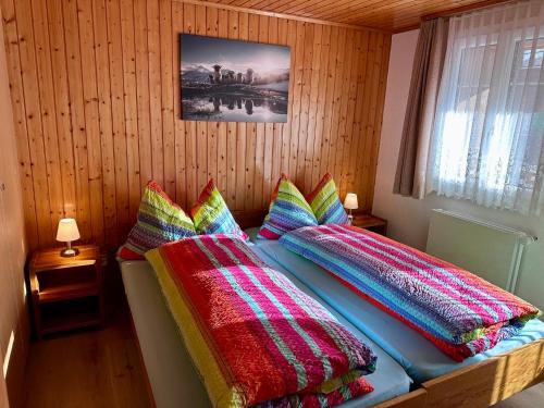 a bedroom with a bed with colorful blankets and pillows at Chalet Alpenheim 1 OG in Bettmeralp