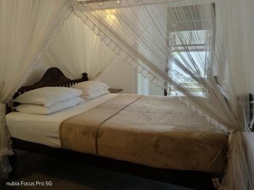 a bedroom with a canopy bed with white sheets and pillows at WG Villa Wathurugama in Kannimahara