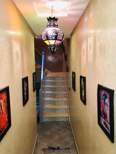 a hallway with a staircase with a chandelier and pictures at Zakar Apartments & Terrace 2 in Mirleft