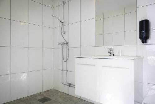 a white tiled bathroom with a sink and a shower at Lia Fjellhotell in Geilo