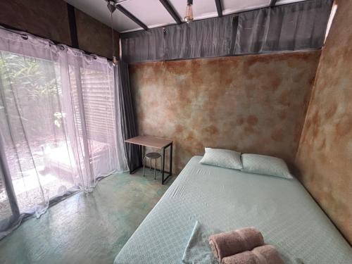 a bedroom with a bed and a table and a window at Green TinyHome 1 in Uvita