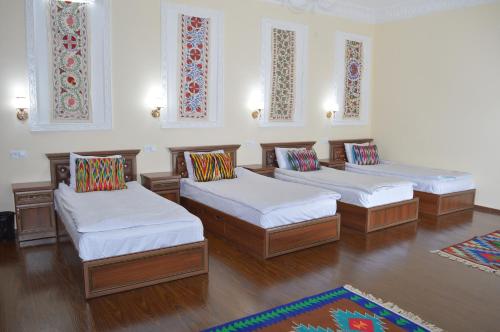 three beds in a room with wood floors and windows at Hostel East Star Khiva in Khiva