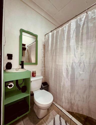 a bathroom with a white toilet and a green cabinet at Sweet Home JACÓ in Herradura