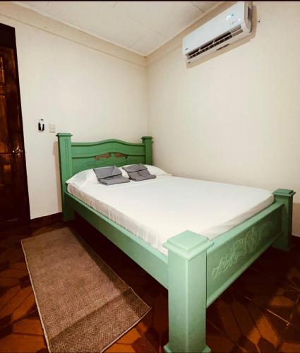 a green bed in a room with a fan at Sweet Home JACÓ in Herradura