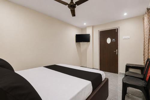 a bedroom with a bed and a tv and a chair at Hotel O Saikrishna Inn in Rājahmundry