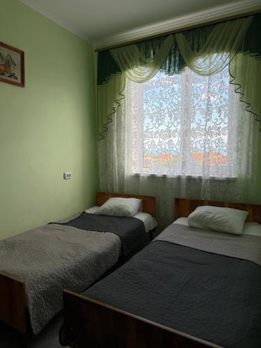 a bedroom with three beds and a window with curtains at Sea Panorama in Karolino-Buhaz