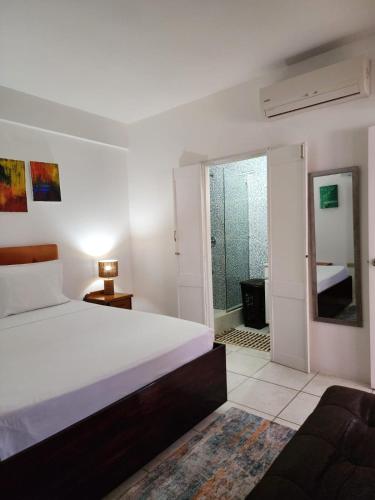 a white bedroom with a bed and a bathroom at Coral Apt Tropical Apartments Tobago in Scarborough