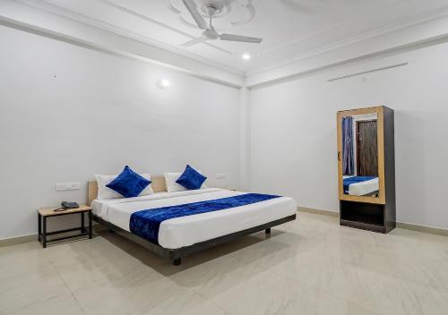 a bedroom with a bed with blue pillows and a mirror at Hotel Avira Inn-Opp Lucknow HighCourt in Lucknow