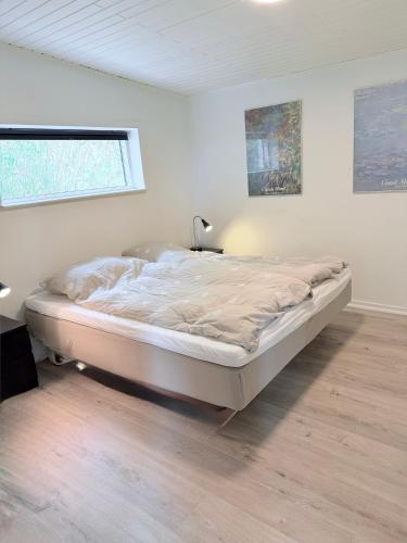a white bedroom with a bed in a room at Det lille hus in Viborg