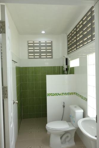 a green and white bathroom with a toilet and a sink at Mook Ing Lay in Koh Mook